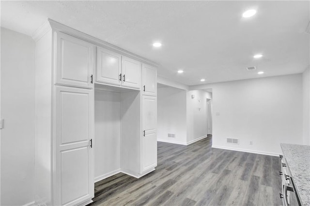 kitchen featuring light stone counters, wood-type flooring, and white cabinets