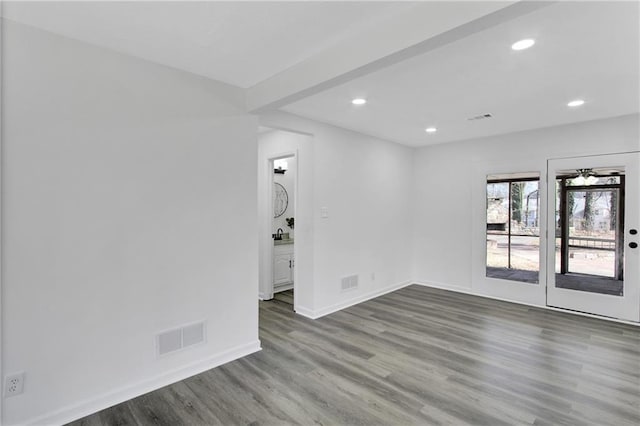 spare room featuring visible vents, baseboards, and wood finished floors