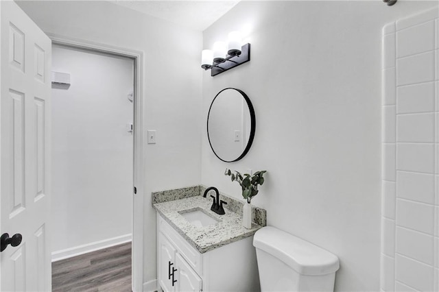 bathroom featuring vanity, toilet, wood finished floors, and baseboards