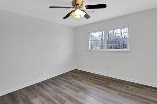 spare room featuring ceiling fan, dark wood-style floors, visible vents, and baseboards