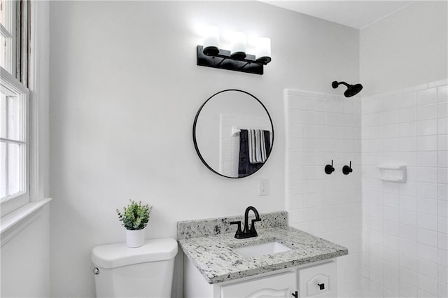 bathroom featuring toilet, vanity, and a tile shower