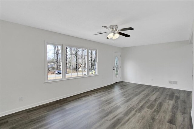 interior space featuring visible vents, baseboards, ceiling fan, and dark wood-style flooring