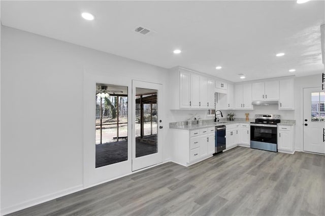 kitchen with electric stove, visible vents, light wood finished floors, and a sink