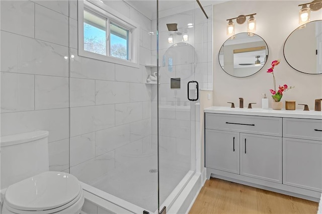 bathroom featuring toilet, hardwood / wood-style floors, an enclosed shower, and vanity