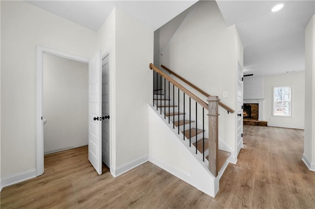 stairway with wood-type flooring and a fireplace