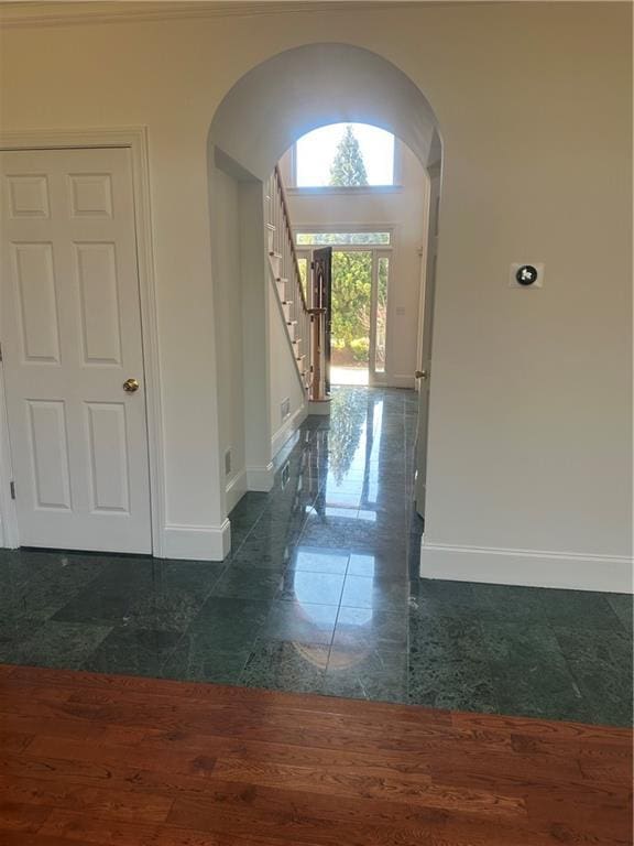 foyer with baseboards, arched walkways, stairs, and granite finish floor