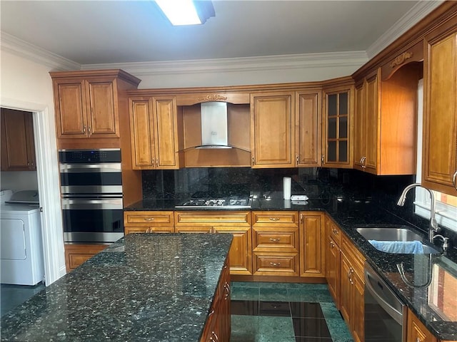 kitchen with washer / clothes dryer, brown cabinets, a sink, stainless steel appliances, and wall chimney exhaust hood