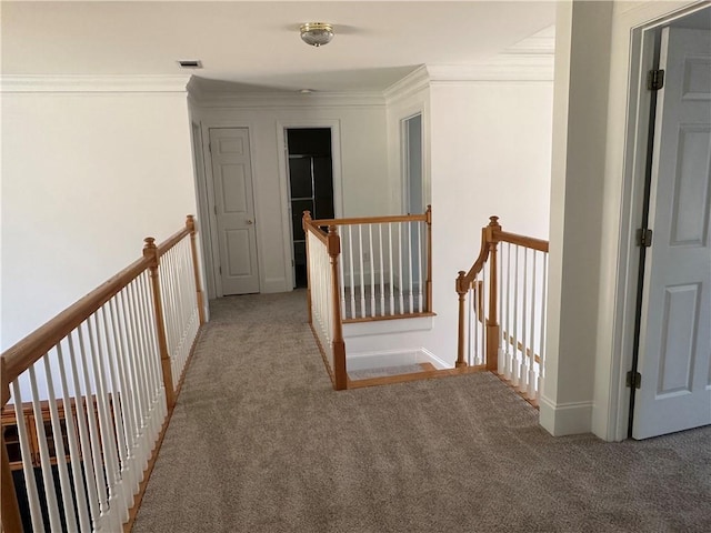corridor featuring visible vents, crown molding, baseboards, carpet flooring, and an upstairs landing