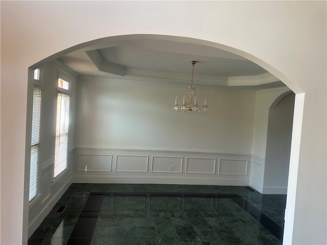 unfurnished dining area with crown molding, a decorative wall, an inviting chandelier, and a wainscoted wall