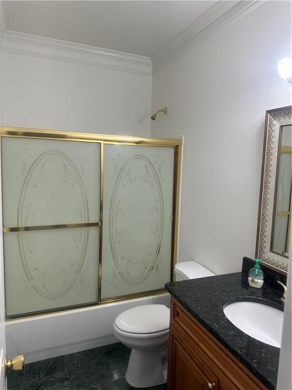 full bathroom featuring toilet, ornamental molding, shower / bath combination with glass door, and vanity