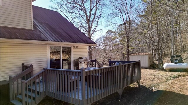 wooden terrace featuring an outbuilding, a grill, and a shed