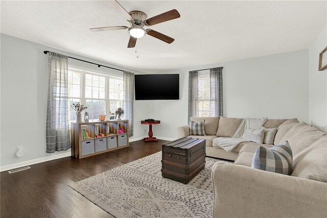 living area with visible vents, baseboards, wood finished floors, and a ceiling fan