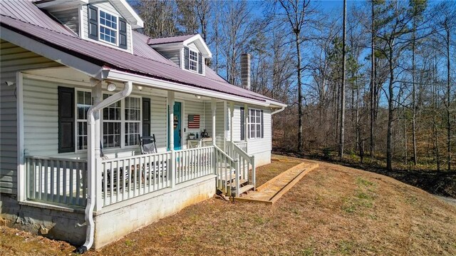 exterior space with french doors, a wooded view, and metal roof