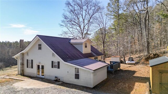 view of front of house featuring a front yard, a forest view, covered porch, and metal roof