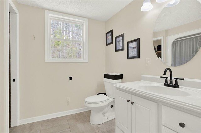 full bath featuring vanity, baseboards, a textured ceiling, tile patterned floors, and toilet