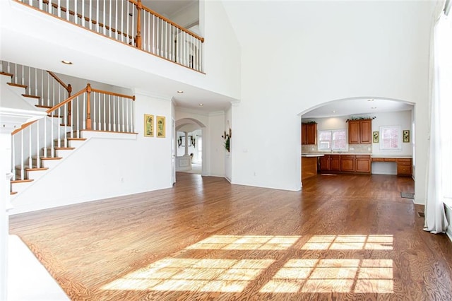 unfurnished living room featuring a towering ceiling and hardwood / wood-style floors