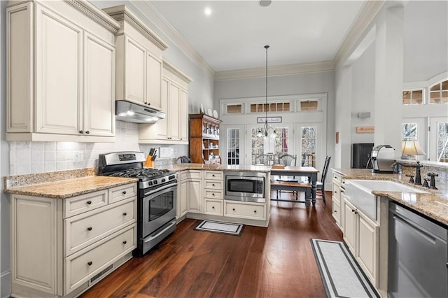 kitchen with sink, light stone counters, decorative light fixtures, ornamental molding, and stainless steel appliances