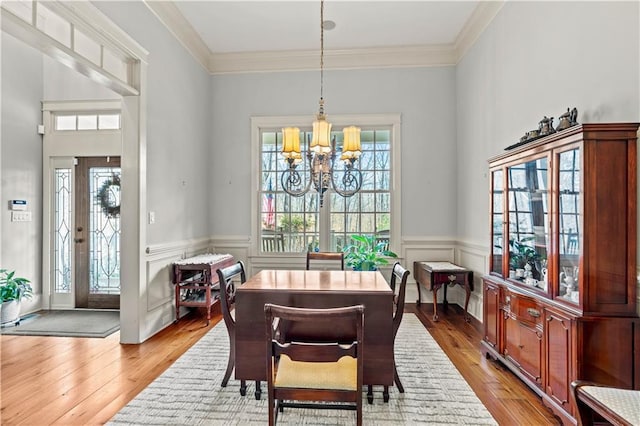 dining area with a notable chandelier, crown molding, a wealth of natural light, and light wood-type flooring