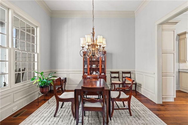 dining space with crown molding, dark wood-type flooring, and a chandelier