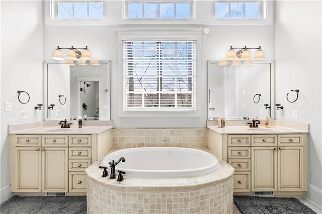 bathroom featuring plenty of natural light, vanity, and tiled tub