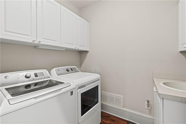 clothes washing area featuring separate washer and dryer, sink, dark hardwood / wood-style flooring, and cabinets