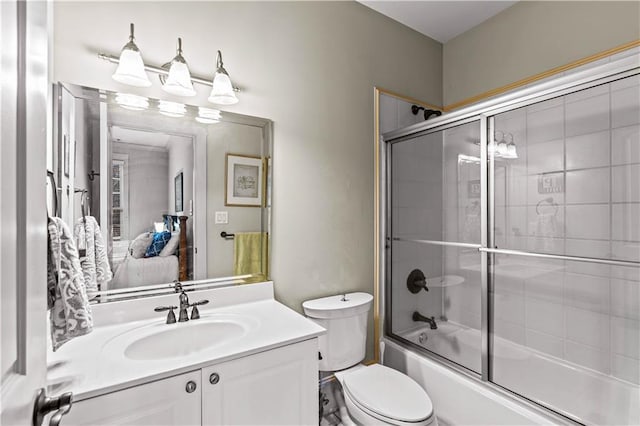 full bathroom featuring toilet, vanity, and bath / shower combo with glass door