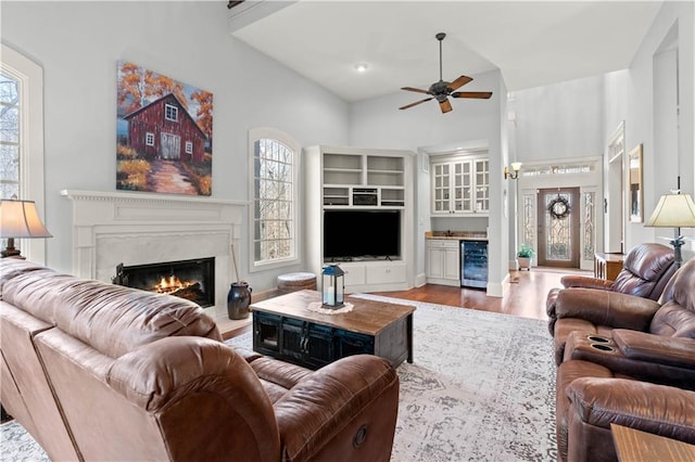 living room featuring wine cooler, hardwood / wood-style flooring, a high ceiling, bar, and ceiling fan