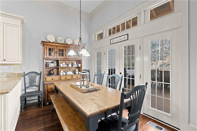 dining room with a high ceiling, ornamental molding, dark hardwood / wood-style flooring, and french doors