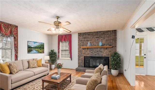 living room with light wood-type flooring, plenty of natural light, a fireplace, and crown molding