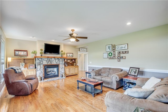 living room with light hardwood / wood-style floors, a fireplace, and ceiling fan