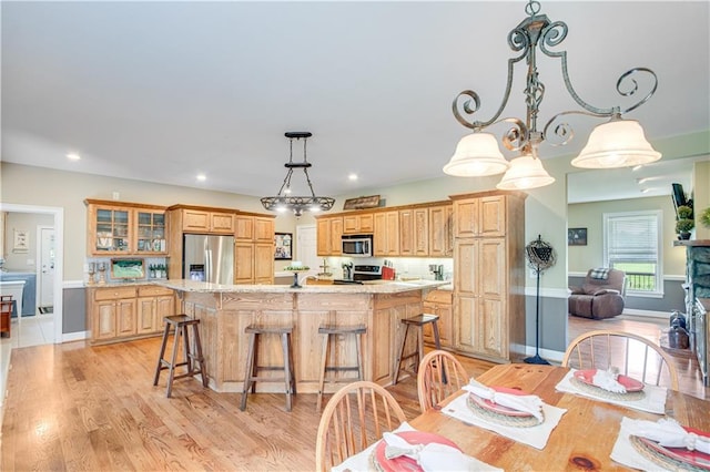 dining room with a notable chandelier, a fireplace, and light hardwood / wood-style flooring