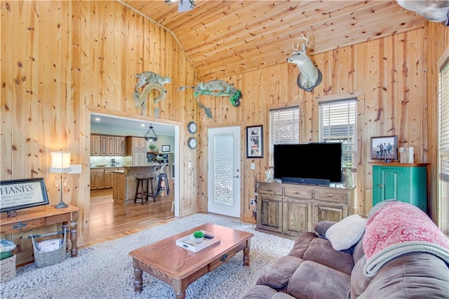 living room with wood walls, wood ceiling, high vaulted ceiling, and light wood-type flooring