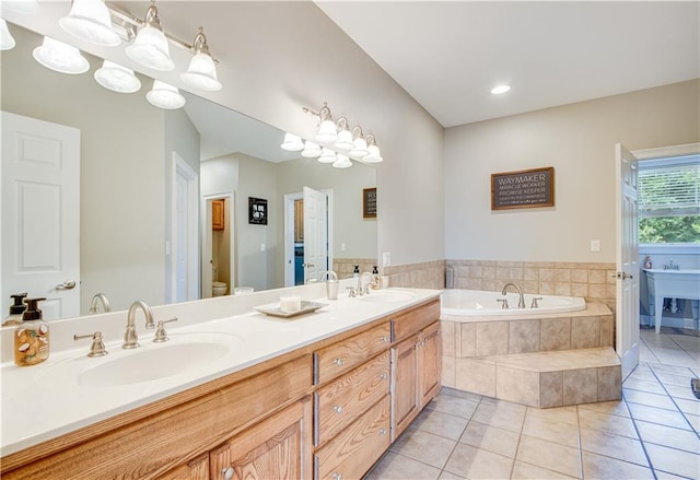 bathroom with dual sinks, tile floors, tiled tub, and vanity with extensive cabinet space