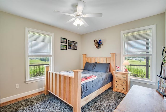 bedroom featuring ceiling fan, dark wood-type flooring, and multiple windows