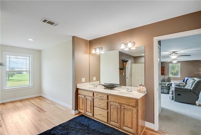 bathroom with double sink, vanity with extensive cabinet space, ceiling fan, and wood-type flooring