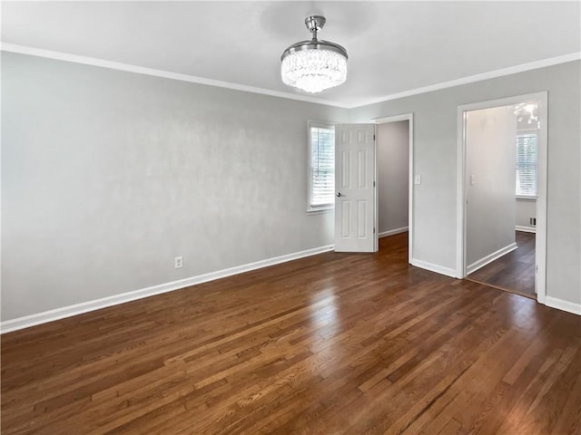 empty room featuring dark wood-type flooring, a chandelier, and a wealth of natural light