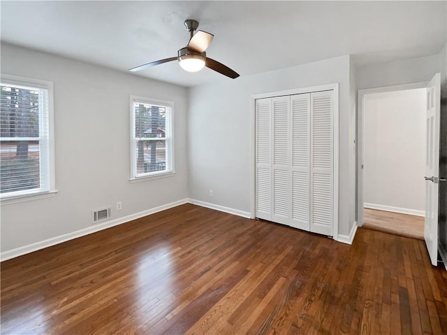 unfurnished bedroom with ceiling fan, dark hardwood / wood-style flooring, and a closet