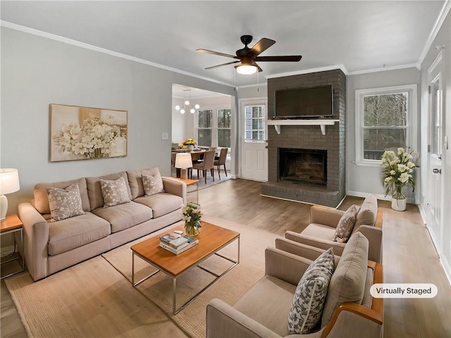 living room featuring crown molding, ceiling fan, a fireplace, and light hardwood / wood-style flooring