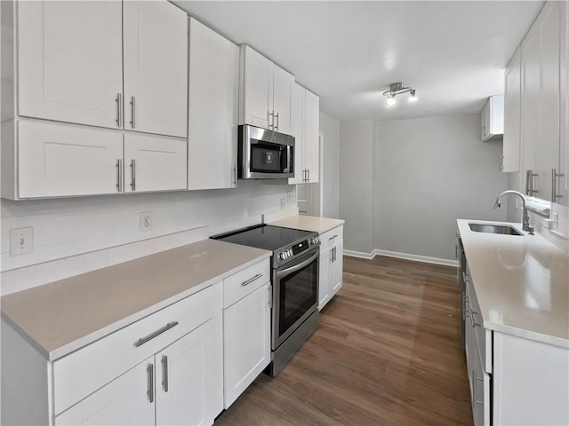 kitchen with appliances with stainless steel finishes, sink, white cabinets, and dark hardwood / wood-style flooring