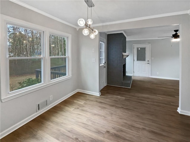 unfurnished dining area featuring dark hardwood / wood-style flooring, ceiling fan with notable chandelier, a fireplace, and ornamental molding