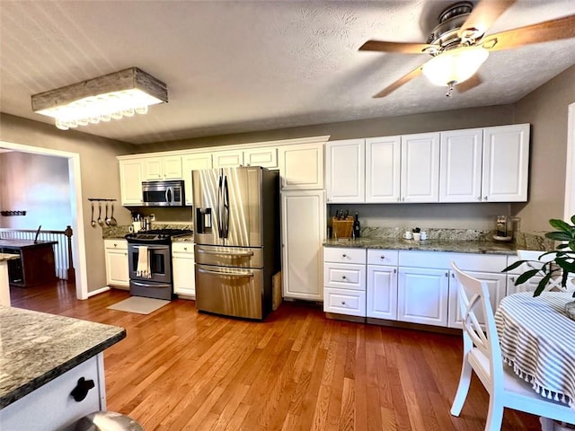 kitchen featuring white cabinets, a textured ceiling, light wood-type flooring, and appliances with stainless steel finishes