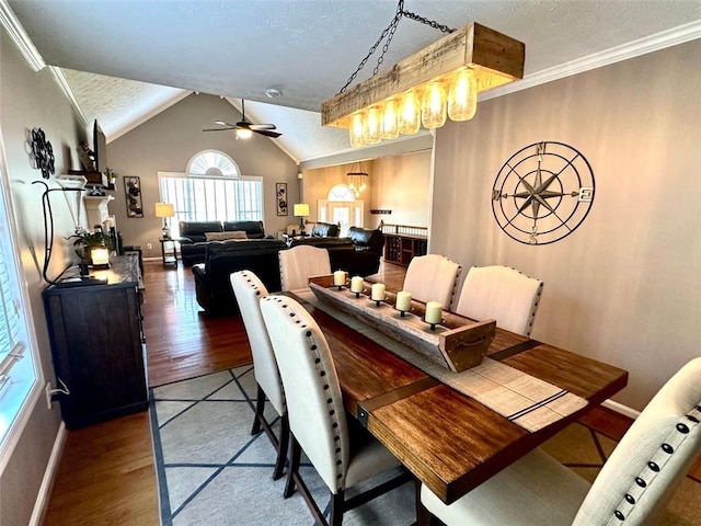 dining room with ornamental molding, dark hardwood / wood-style floors, a textured ceiling, ceiling fan with notable chandelier, and lofted ceiling