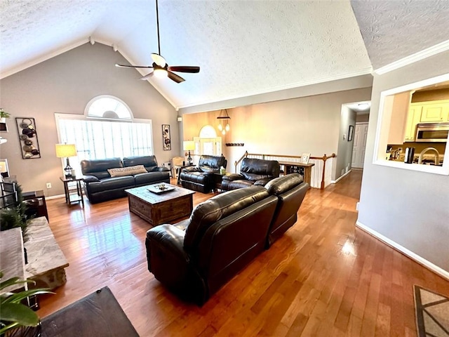 living room with a textured ceiling, vaulted ceiling, ornamental molding, and wood-type flooring