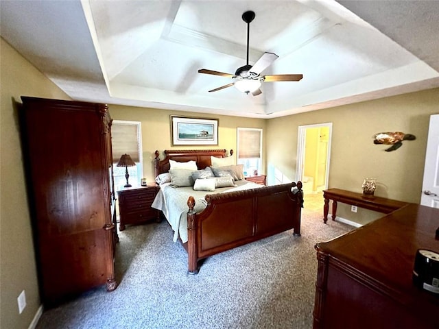 carpeted bedroom featuring ceiling fan, a raised ceiling, and connected bathroom