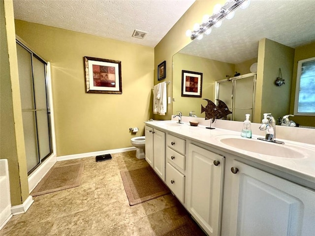 bathroom with toilet, vanity, a textured ceiling, and a shower with shower door