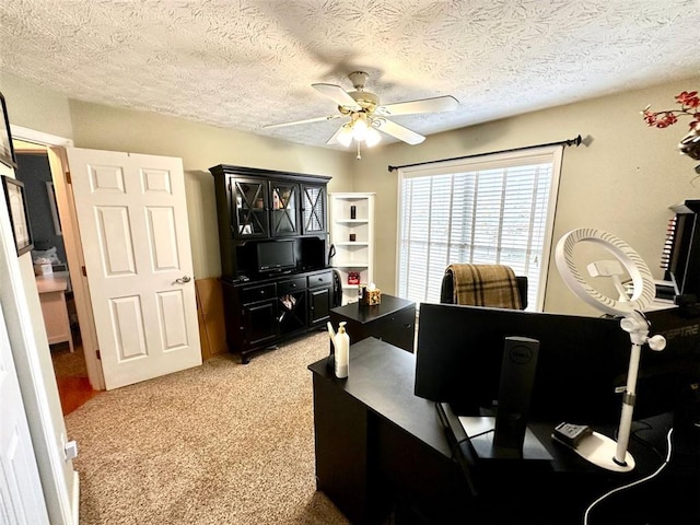 carpeted office space with a textured ceiling and ceiling fan