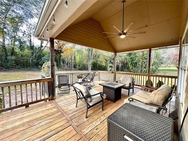 wooden terrace featuring ceiling fan and an outdoor living space with a fire pit