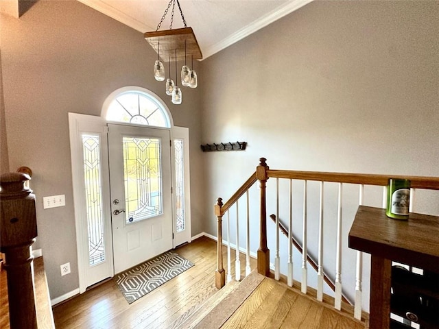 foyer featuring wood-type flooring, crown molding, and vaulted ceiling