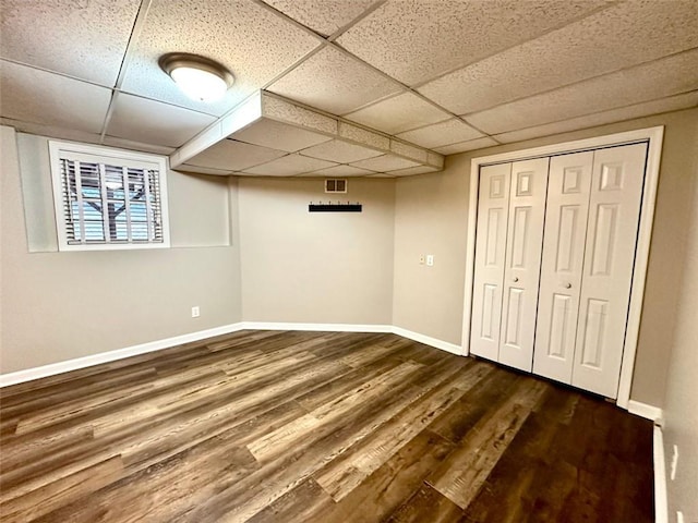 basement featuring a drop ceiling and dark wood-type flooring