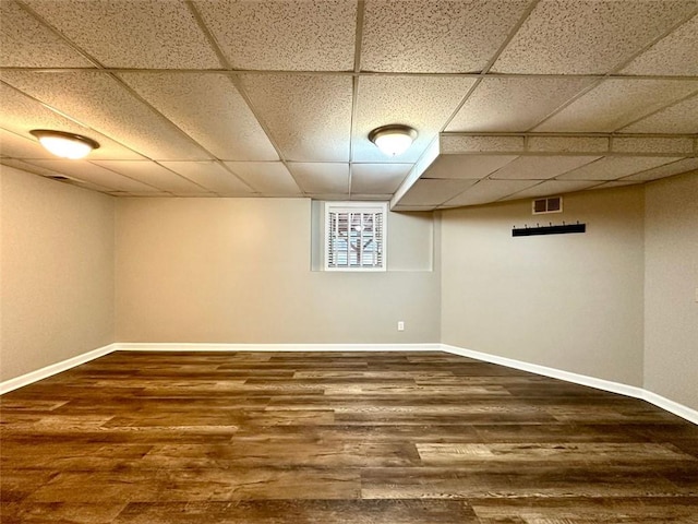 basement with a paneled ceiling and dark hardwood / wood-style floors